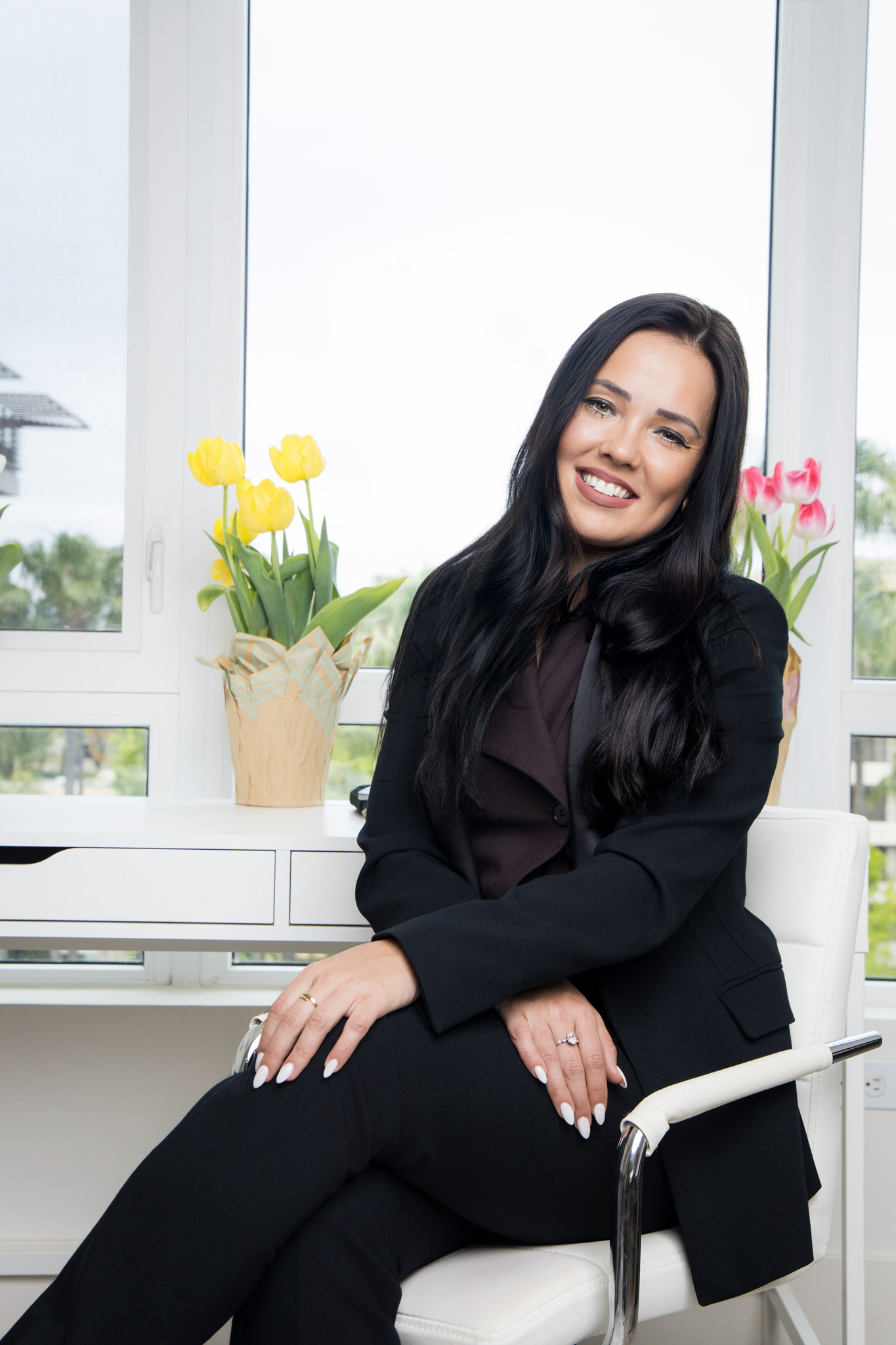 Dr. Alena Schuss sitting in black suit with arms crossed smiling